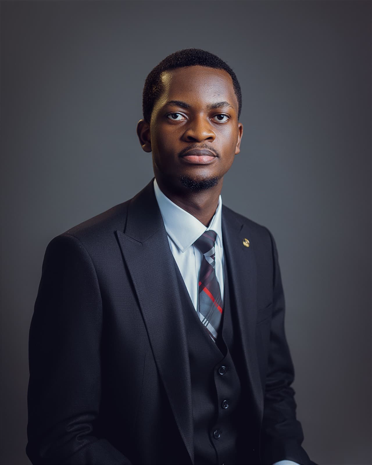 Ife Abimbola-Olulesi in a three-piece suit, photographed against a plain studio backdrop